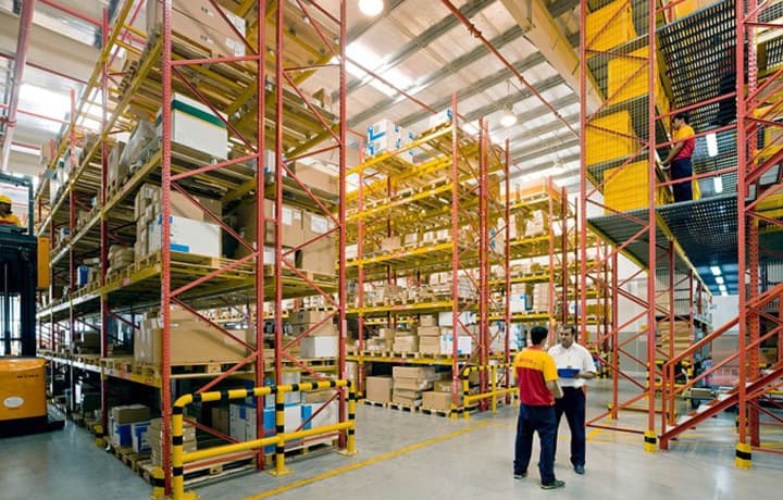 Curier DHL Express preia un colet pentru transport international, reprezentand serviciile DHL International Romania